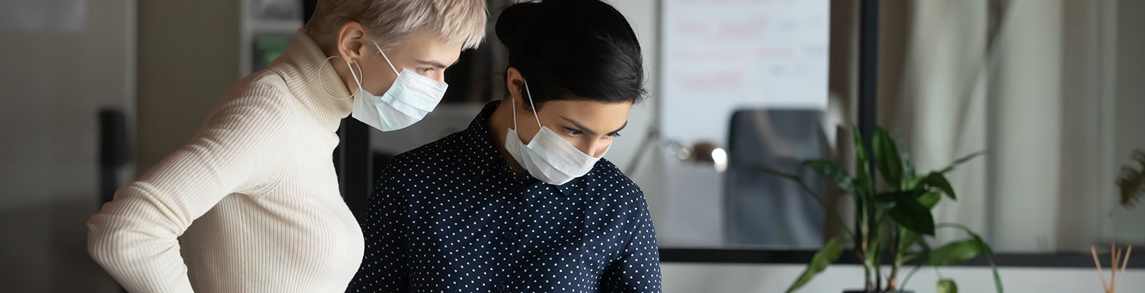 Two women with masks looking at data